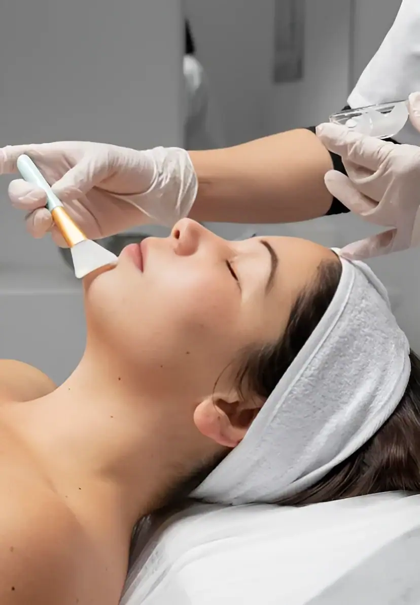 Woman receiving facial treatment with a device in a clinic setting.