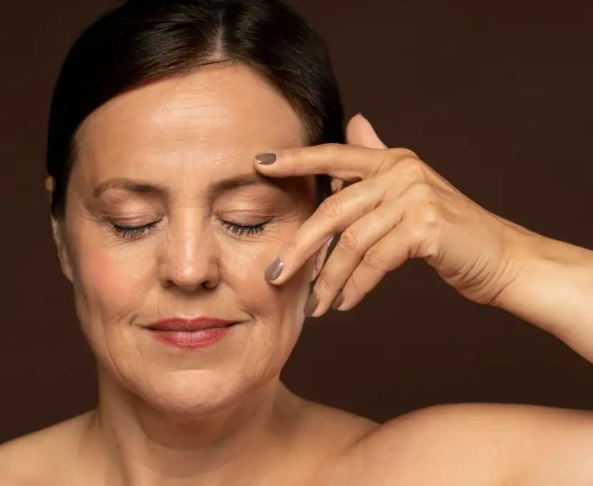 Relaxed woman with closed eyes touching her forehead with her fingers.
