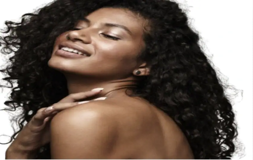 Beautiful woman with curly hair smiling and looking over her shoulder.