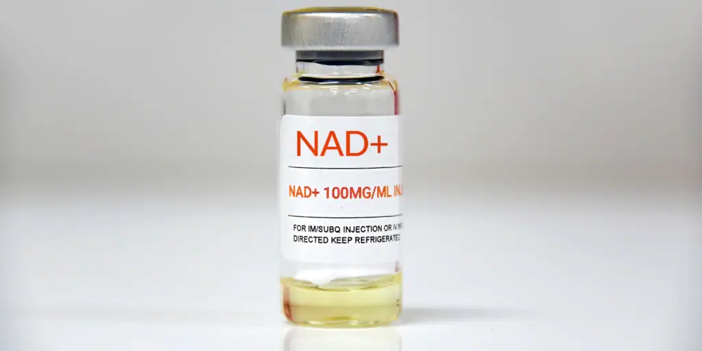 NAD+ supplement vial with a silver cap on a plain background.