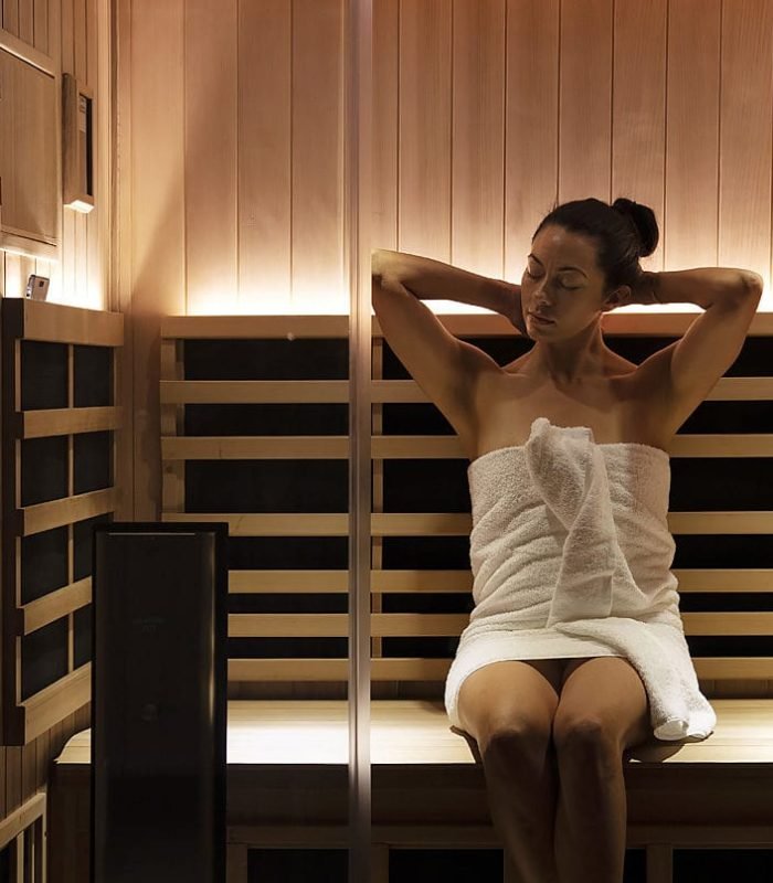 Relaxing woman in a sauna with a towel wrapped around her body.